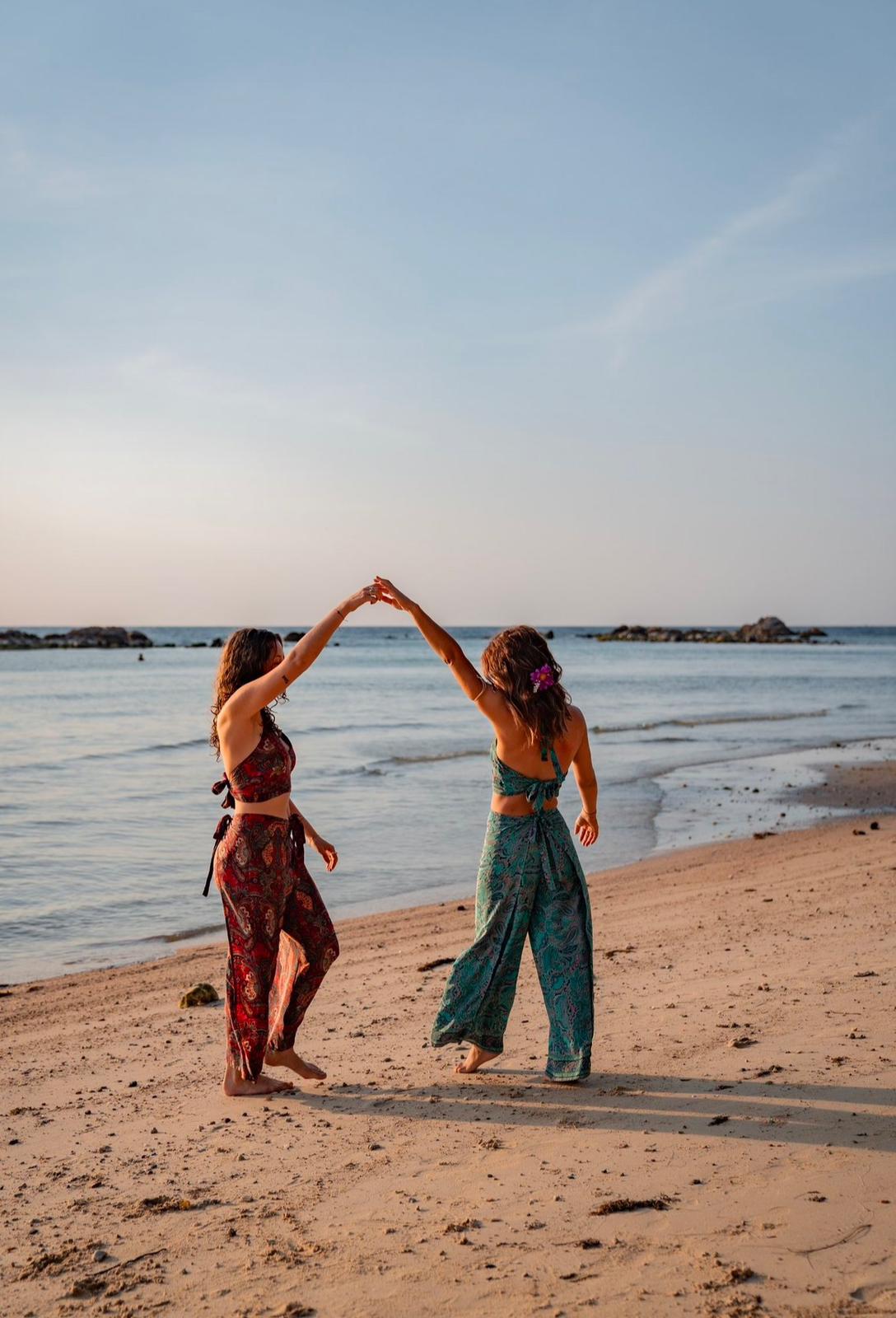 A circle of people sitting cross-legged, meditating with hands in a prayer position. Soft, warm lighting.