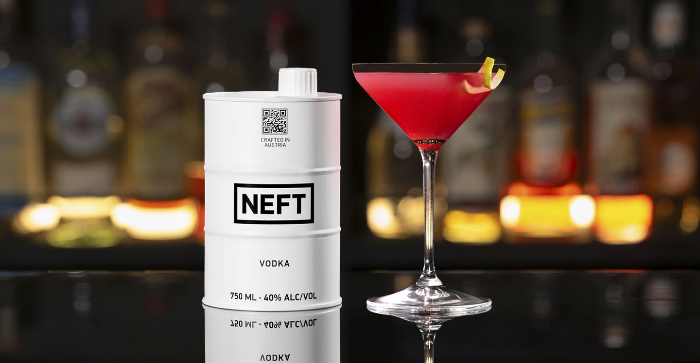 A NEFT Barrel and a glass of Pomegranate Martini on a bar counter.