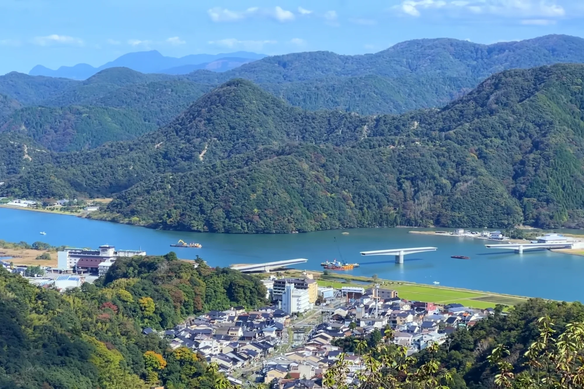 View from the Kinosaki ropeway summit over forested ridges to the river mouth and the sea.