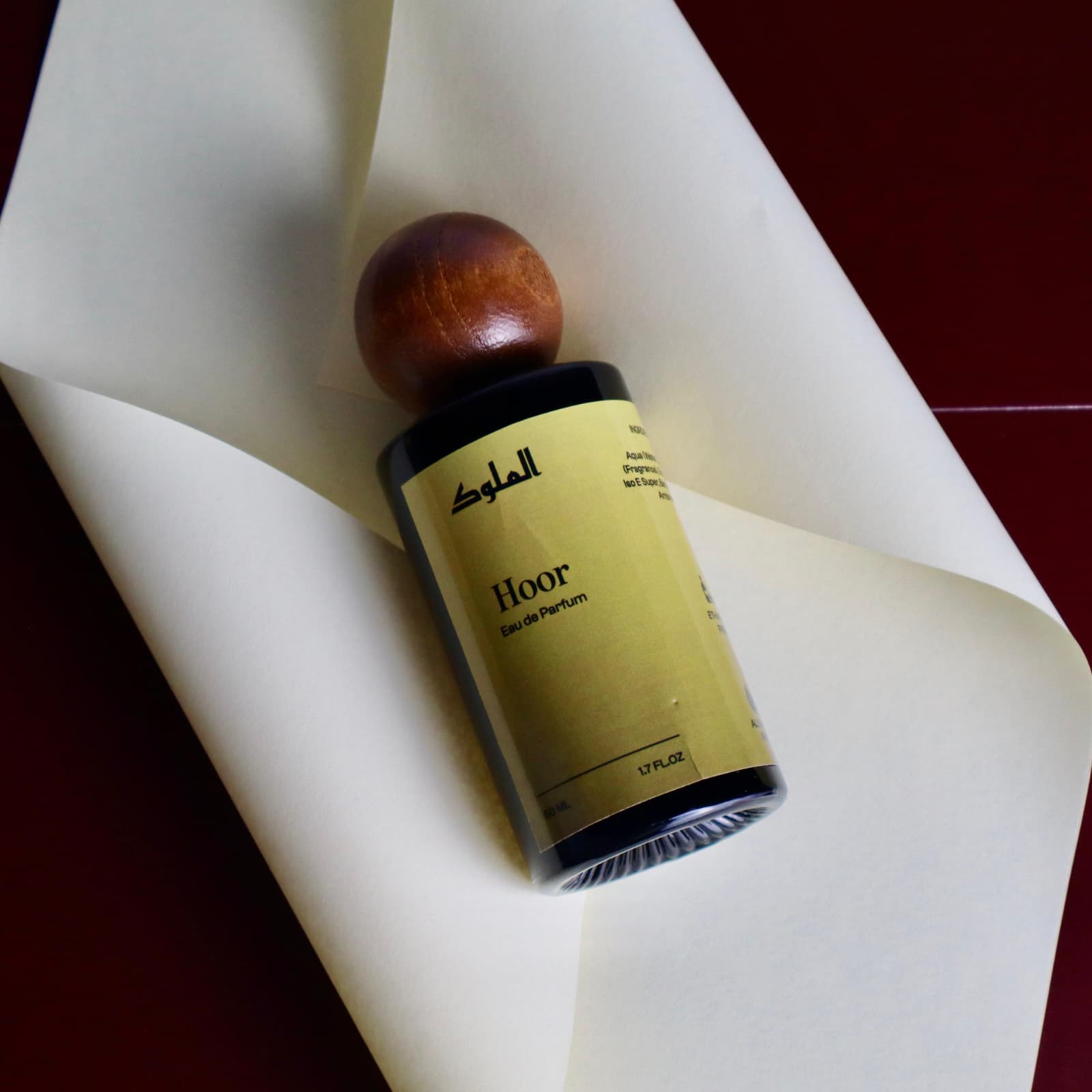 Hoor perfume bottle with wooden cap and gold label on neutral white background.