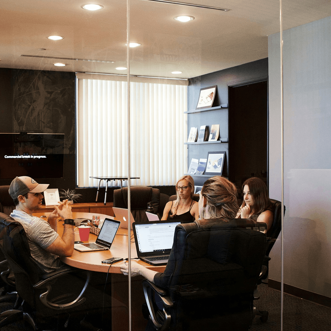 Multiple hands brainstorming around a table with papers and pens.