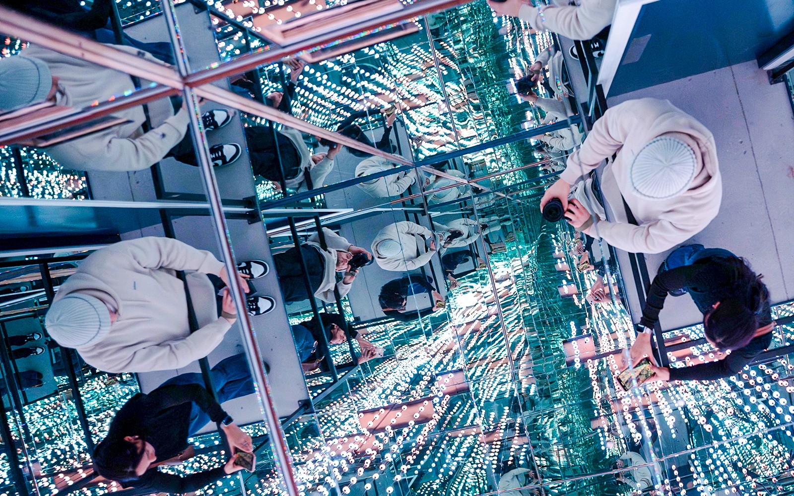 Guests exploring mirrored room at World Of Illusions with reflections and lights.