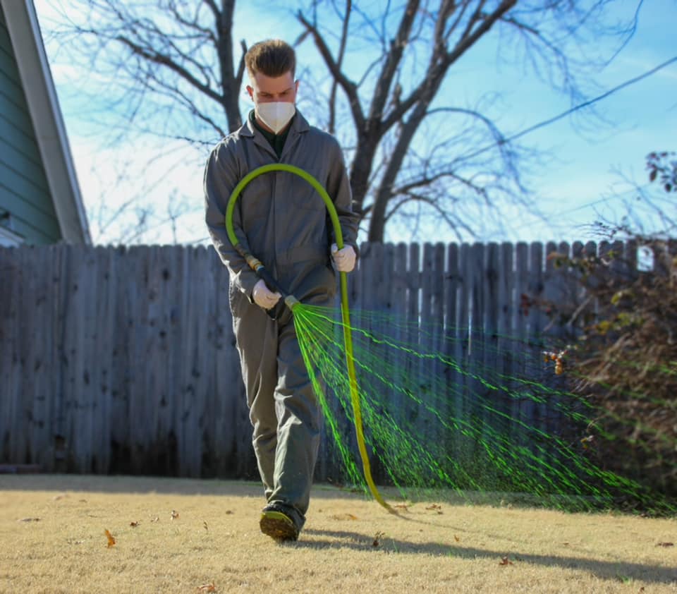 Technician applying eco-friendly weed control treatment on a residential lawn.