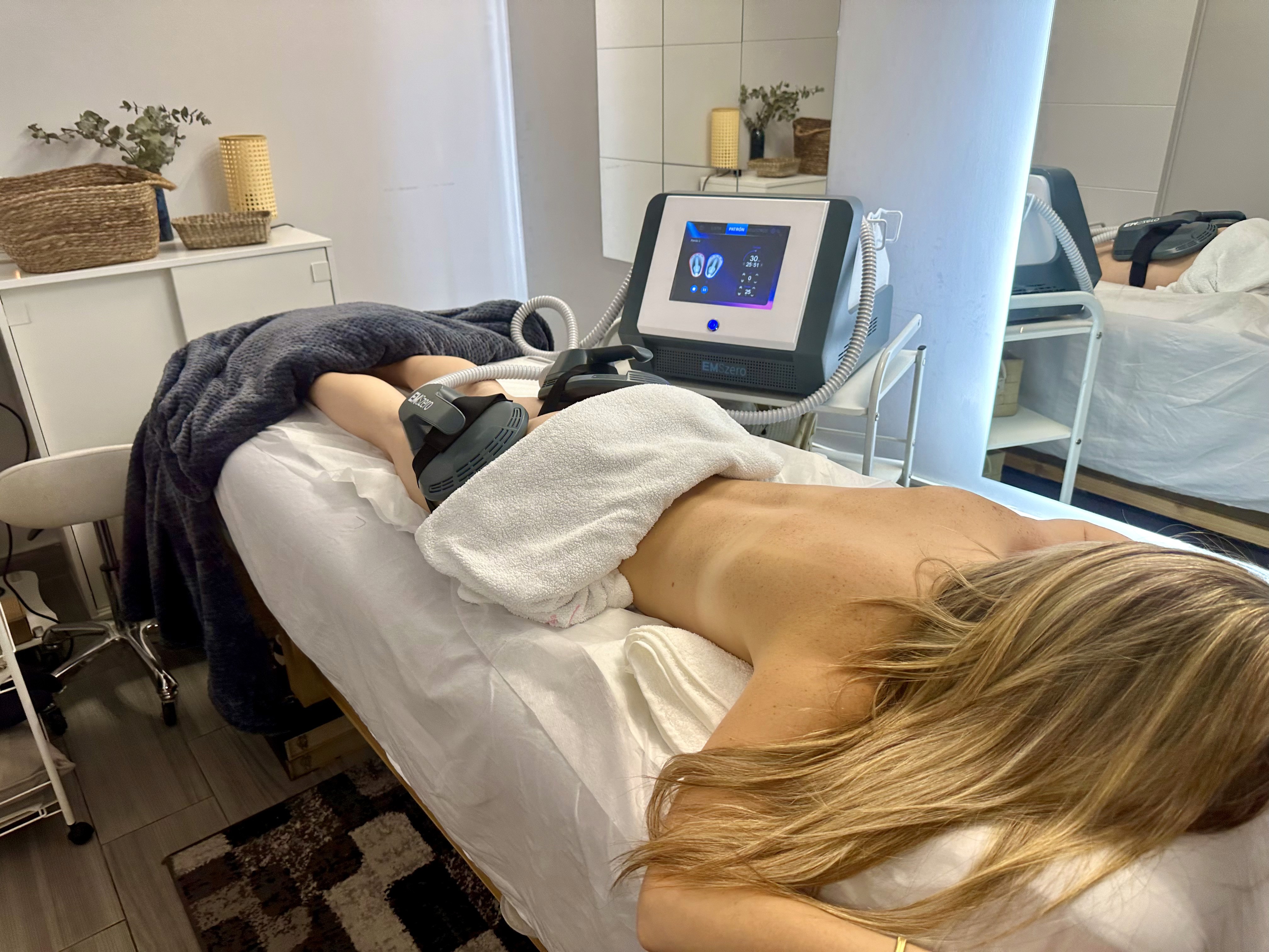 A woman lying down with a towel wrapped around her head, her face glowing with facial oil. She has a peaceful expression, enjoying a skincare treatment.