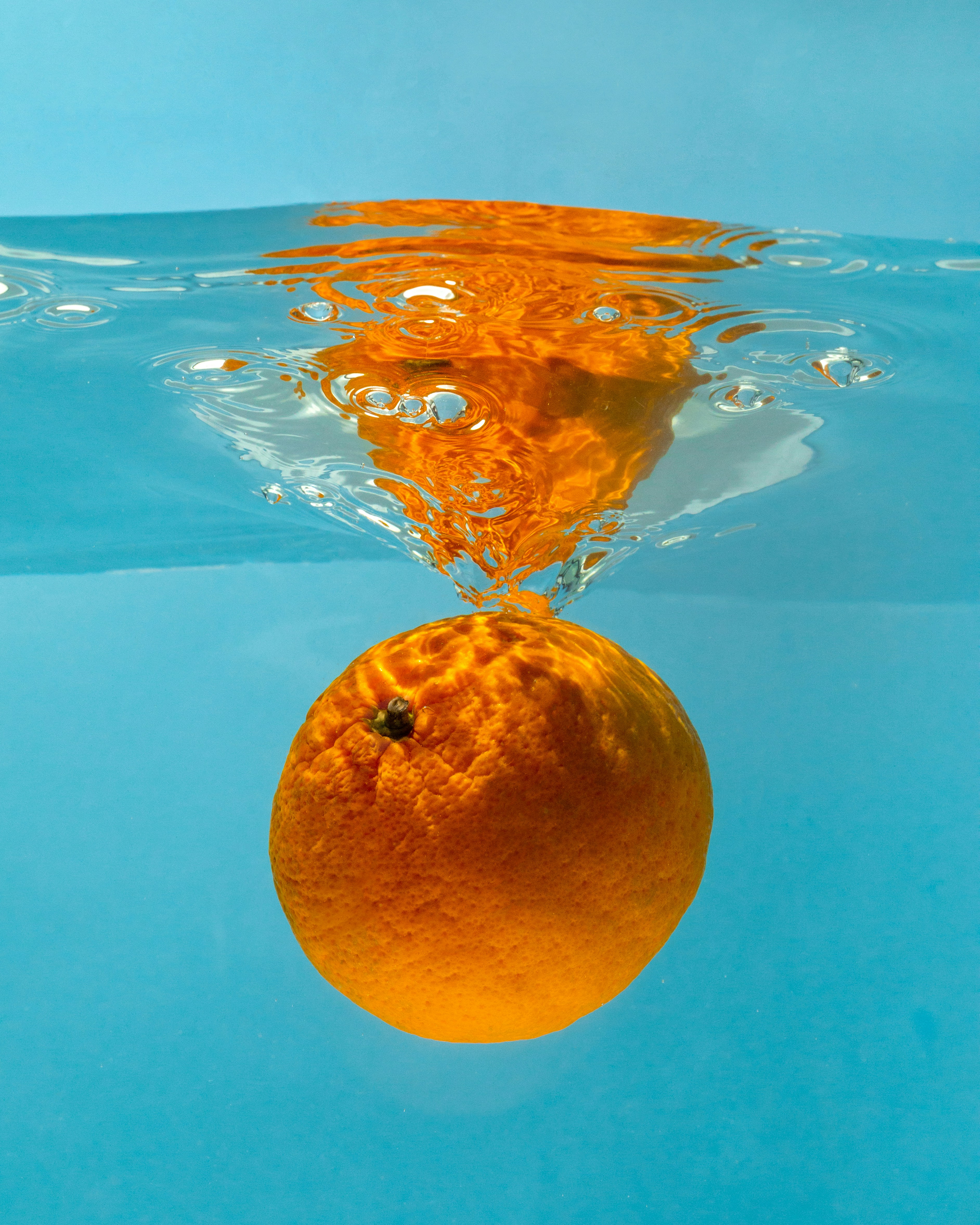 An orange floating in a pool of water