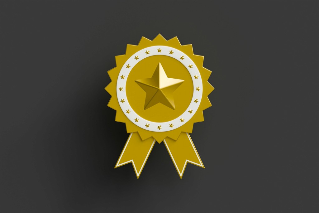 A gold star medal with a ribbon on a dark background symbolizes achievement, excellence, and recognition. The star, surrounded by a circular design with smaller stars, highlights the prestige and honor associated with this award.