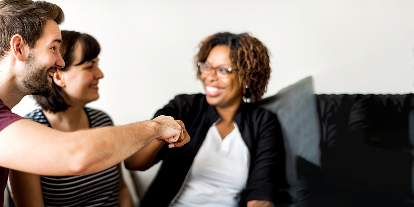 A diverse group of smiling people sharing a fist bump in a casual indoor setting