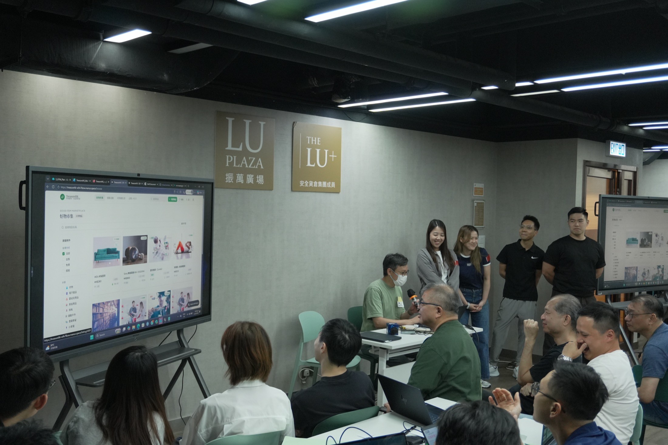 華懋集團 AI Hackathon 參加者在屏幕旁展示 MoveHK pitch deck。