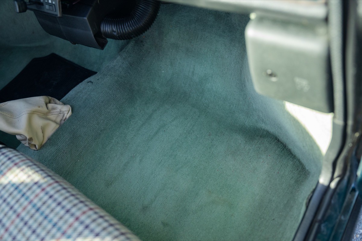Interior view of a car showing a clean floor mat and part of the driver's seat.