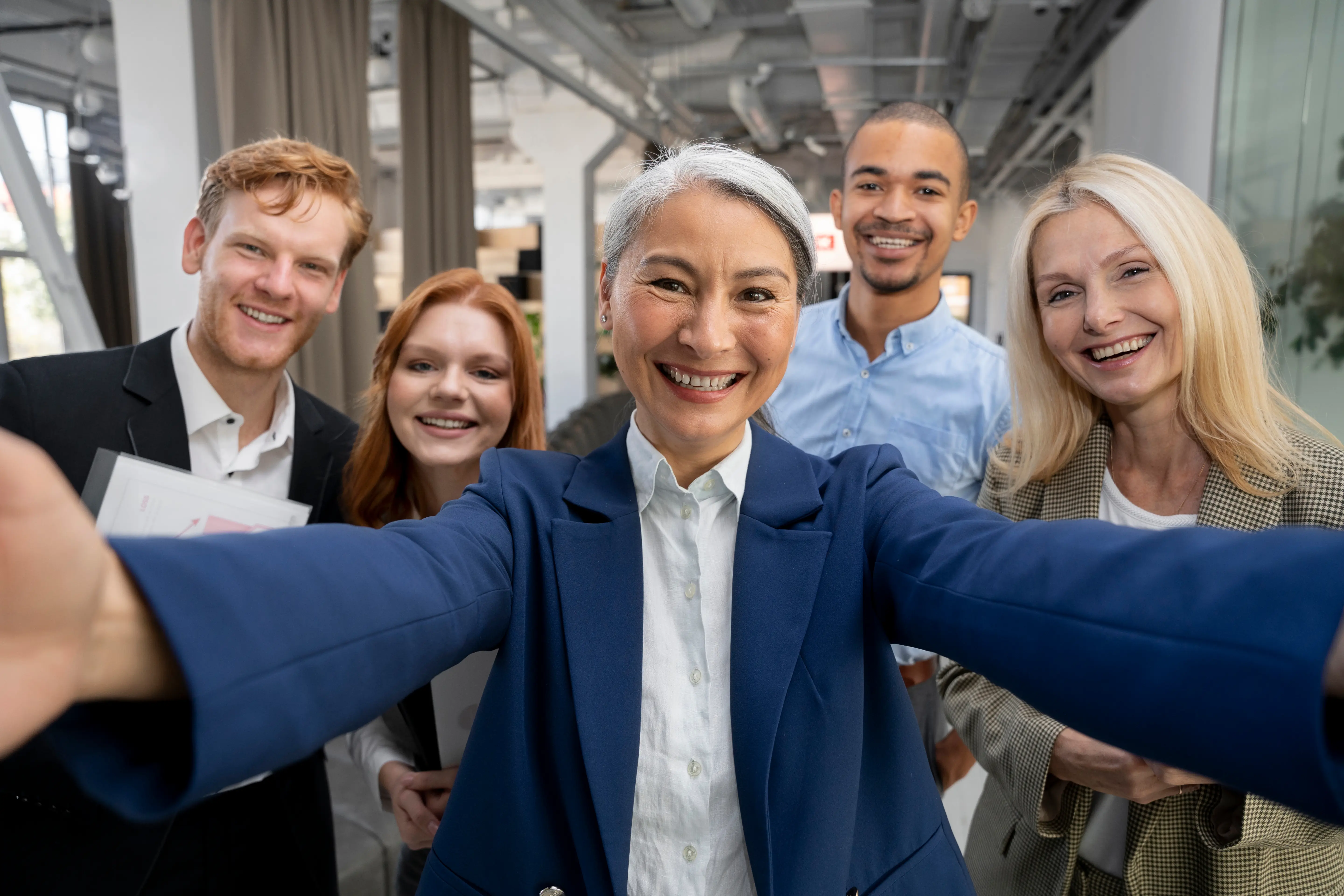 Selfie Photo of five people, in a professional setting, smiling.