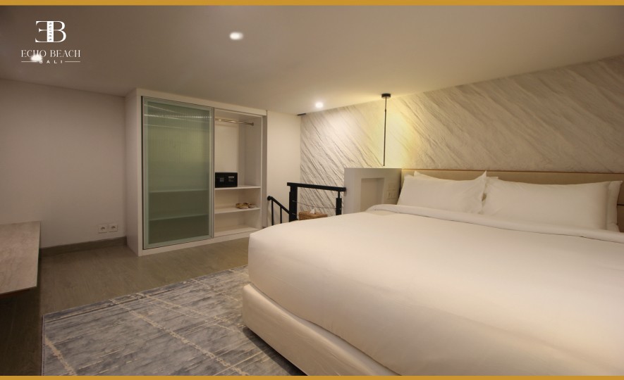 Mezzanine bedroom of the Echo Beach Suite apartment in Canggu, Bali, with a large bed, closet storage, and a safe.