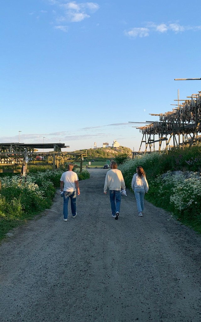 3 people walking on a gravel round among flower beds.
