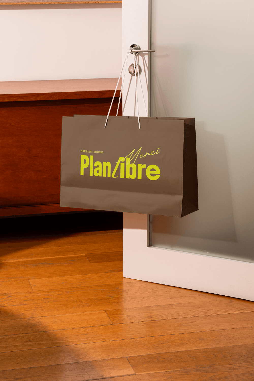 A man in a grey shirt sits in a dim office, gazing seriously at a computer screen. Blinds and office supplies create a focused and professional atmosphere.