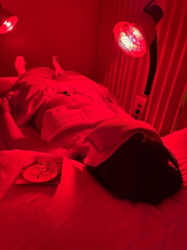Client lying under red heat lamps during relaxation therapy session