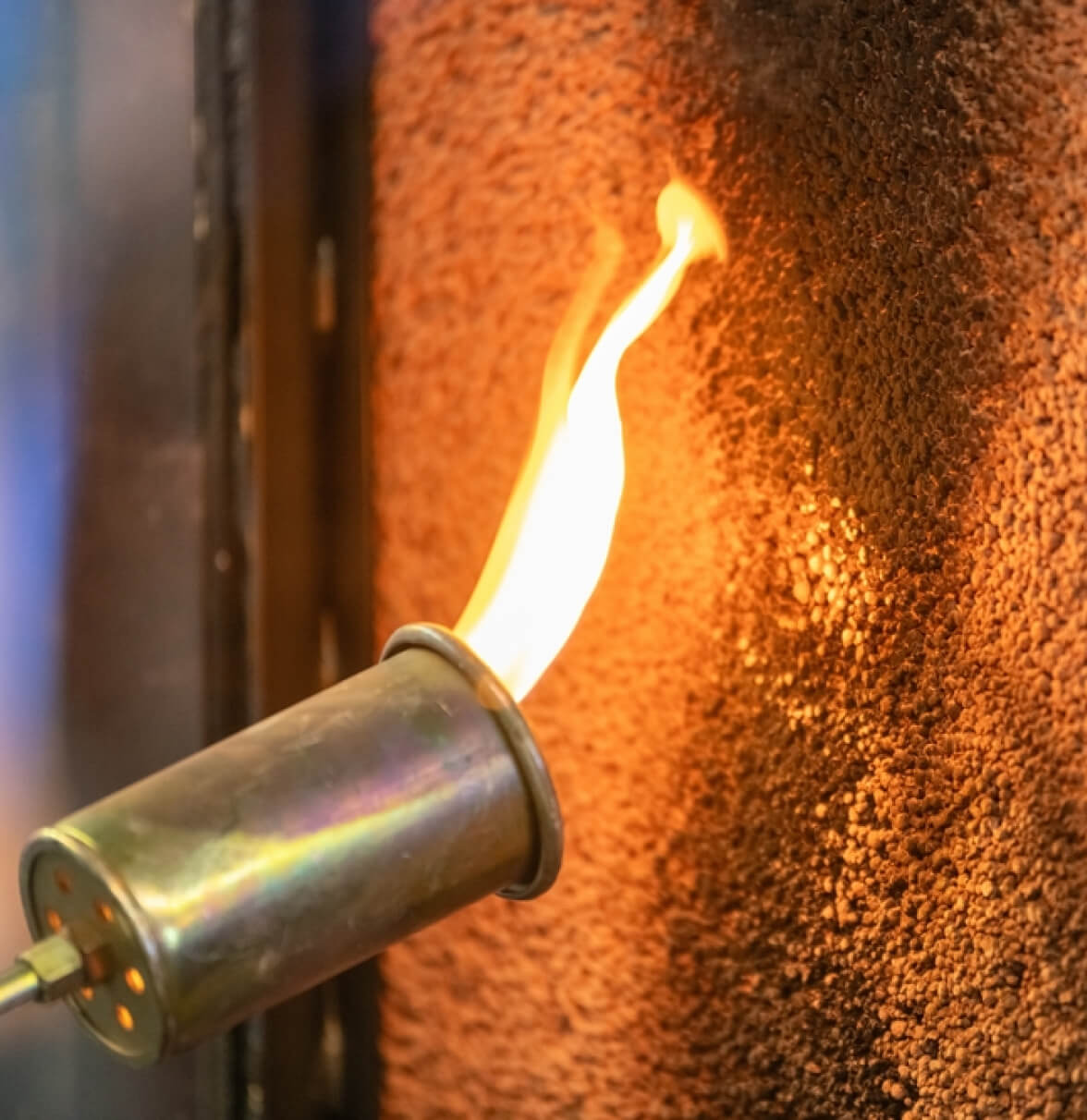 A close-up of a torch flame igniting a surface, creating a warm glow and intense colors.