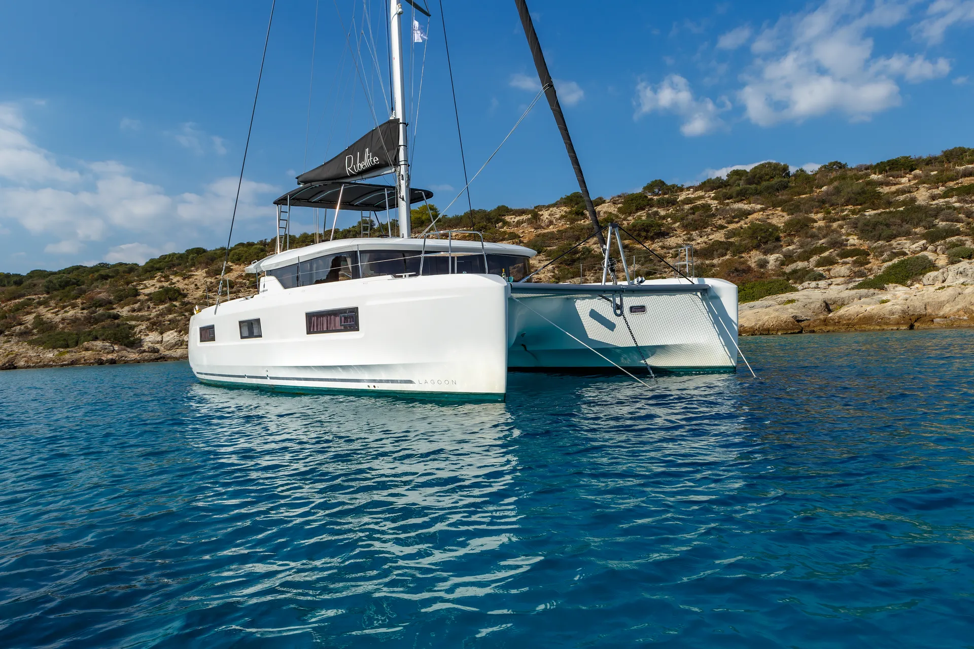 White Rock 36 speedboat with captain at helm cruising calm blue waters near Paros coastline with hills in background.