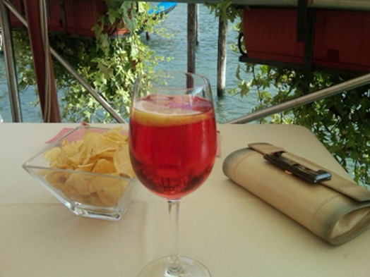 A photo of a glass with lemon juice, some chips in a glass bowl and a wallet.