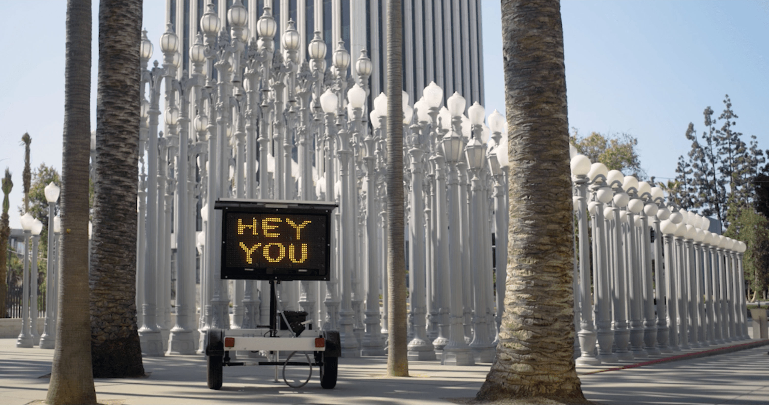 Road sign that says "Hey You" in front of Urban Light by Chris Burden at LACMA