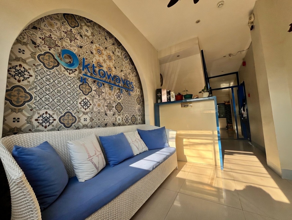 Oktowaves Hotel lobby and reception area with blue sofa and logo wall in Nasugbu