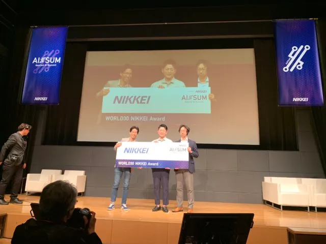 The Mujin team takes a photo with the World 30 NIKKEI award at the Applied AI Summit