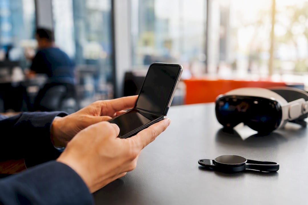 Hands holding foldable phone with wearable devices nearby