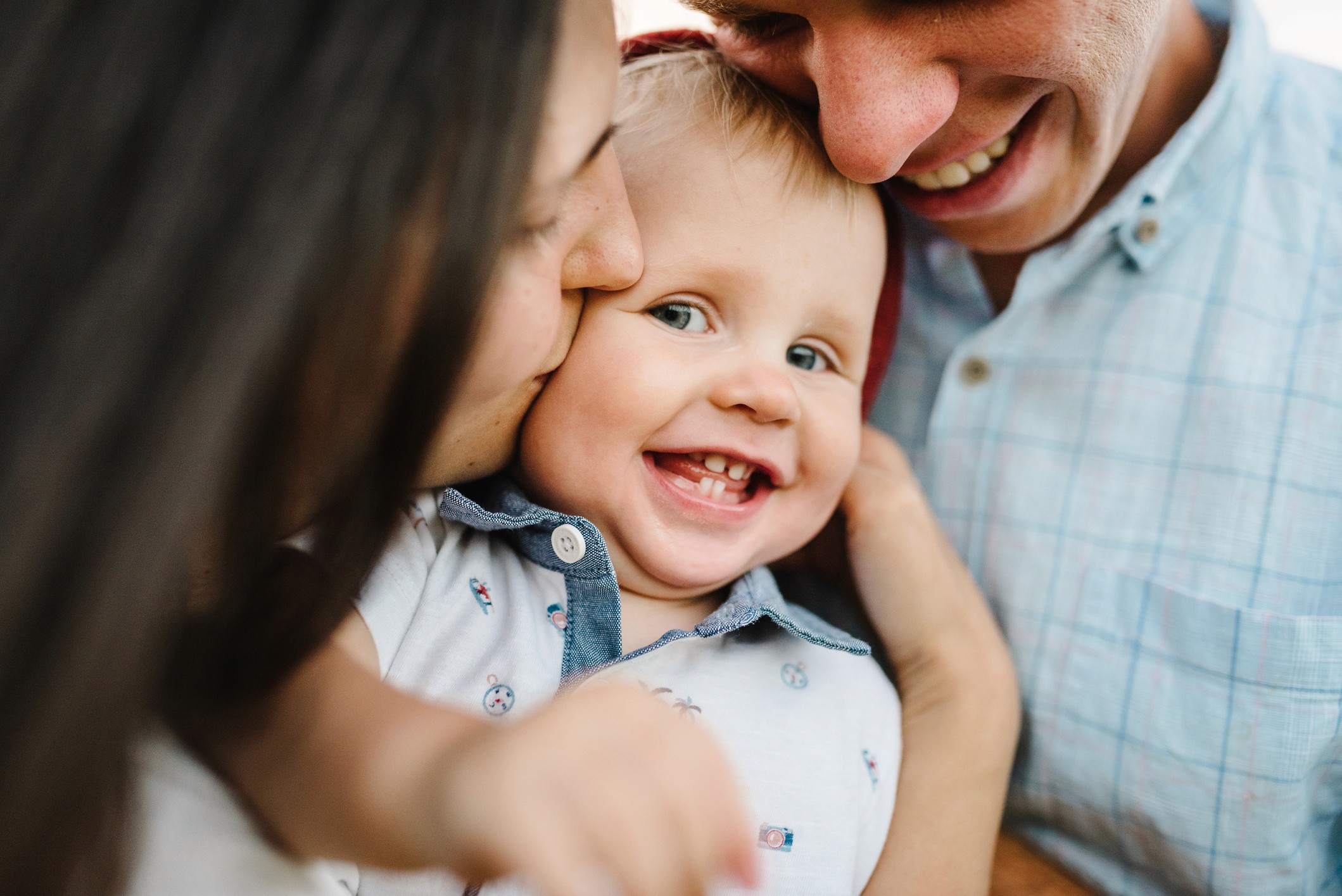 Vater sitzt mit Baby auf dem Schoß am Laptop, wirkt zufrieden und beansprucht – Hinweis auf Unterstützungsangebote – Die Online-Plattform für Vereinbarkeit.
