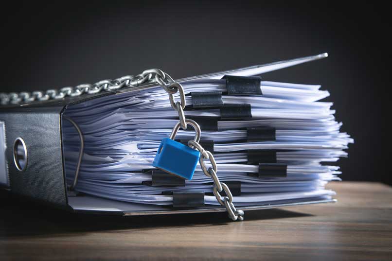 Papers and folders inside a binder, wrapped with a chain and padlock.