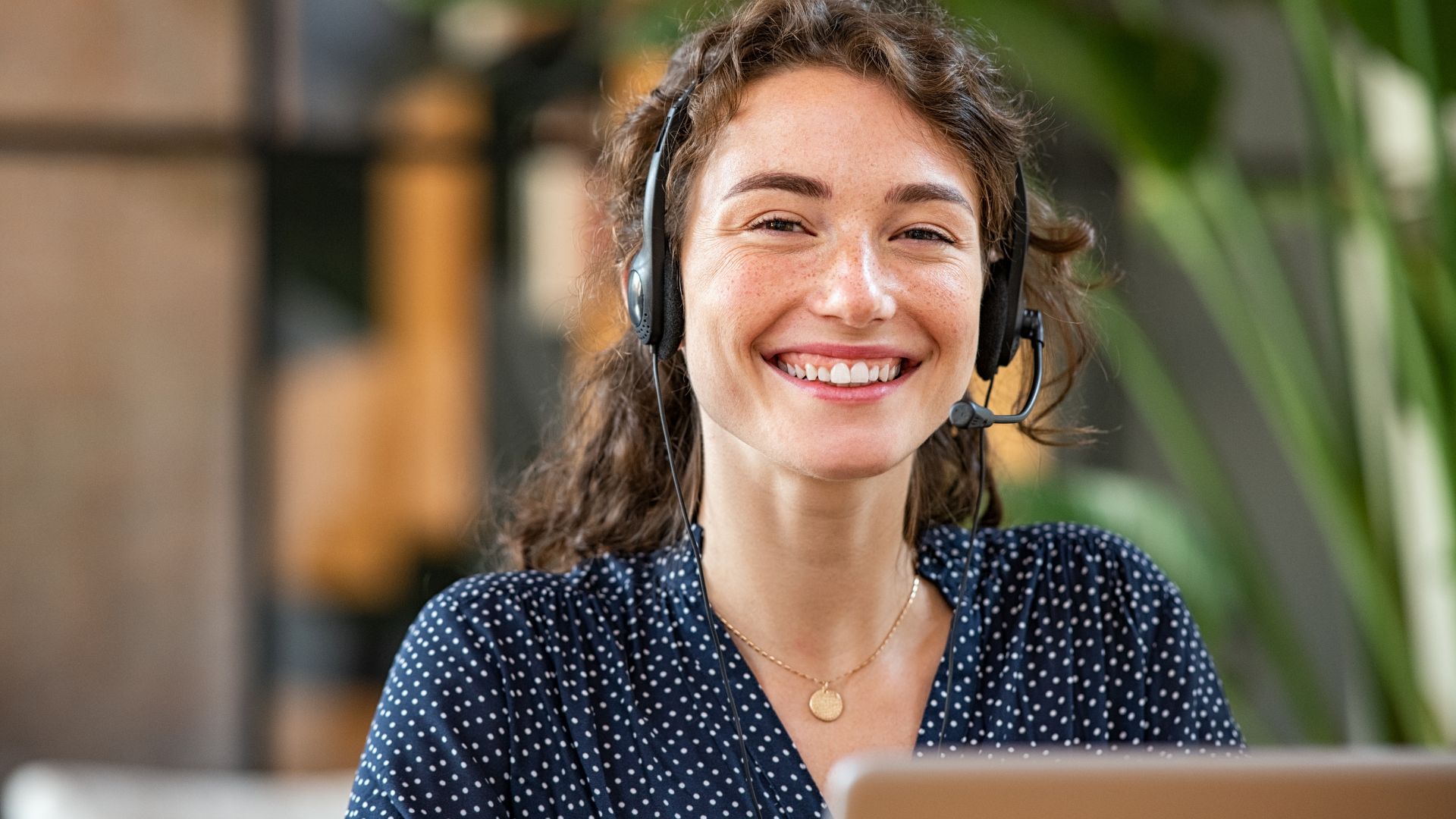 A customer service agent in a headset, smiling mid-conversation
