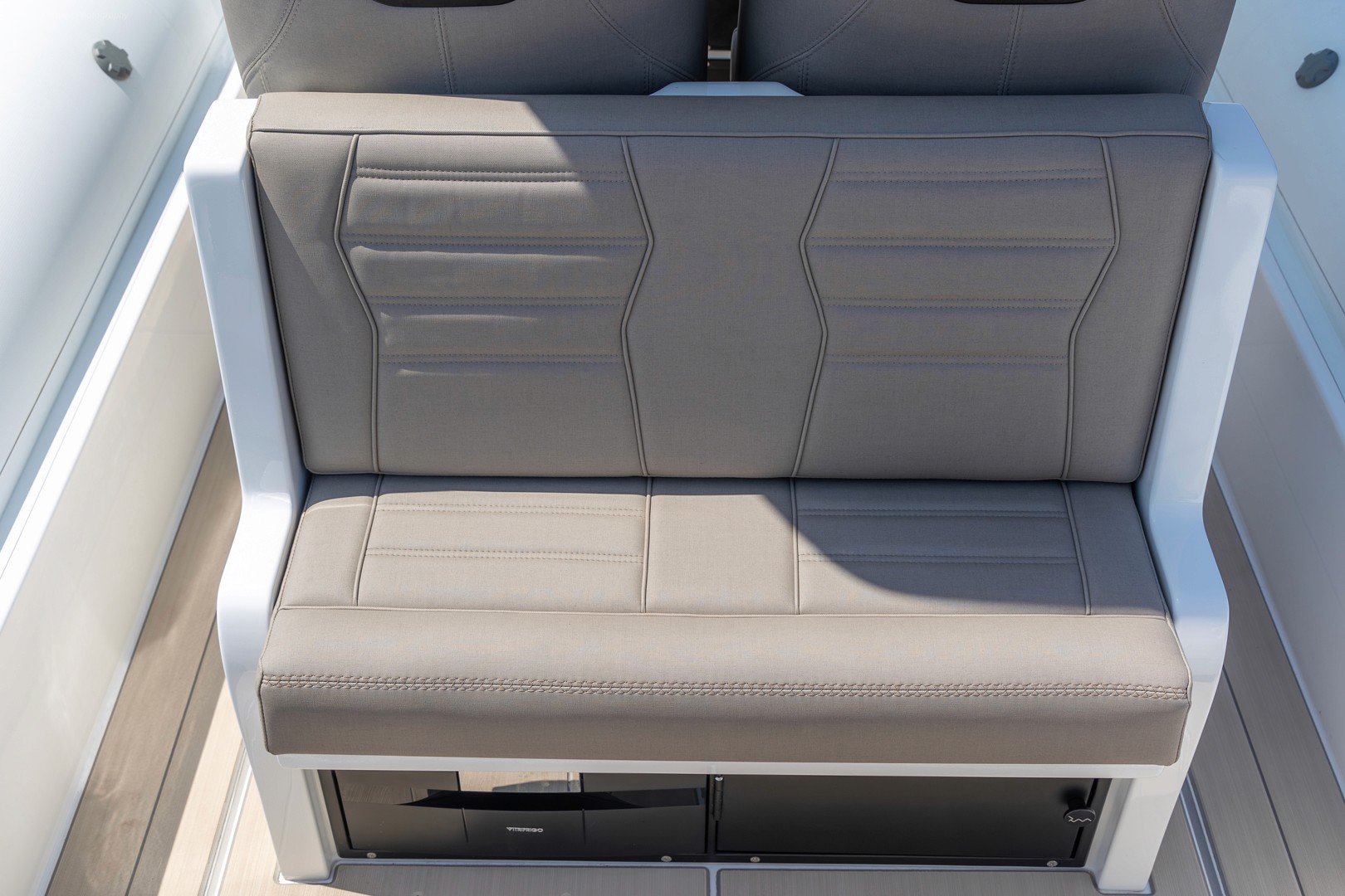 White Rock 36 rigid inflatable boat with twin outboard engines cruising in calm turquoise waters near Greek coastal town with mountains in background.