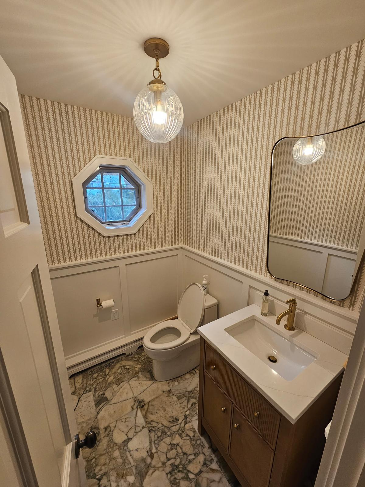 Bathroom renovation with custom vanity, marble flooring, and brass fixtures