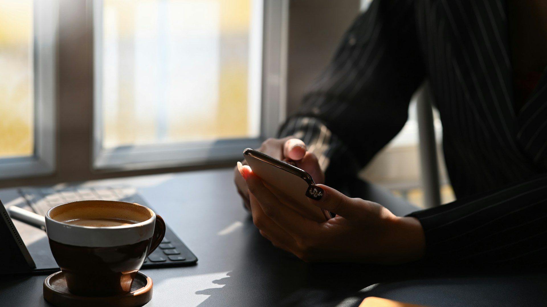 A person using a phone in front of a keyboard
