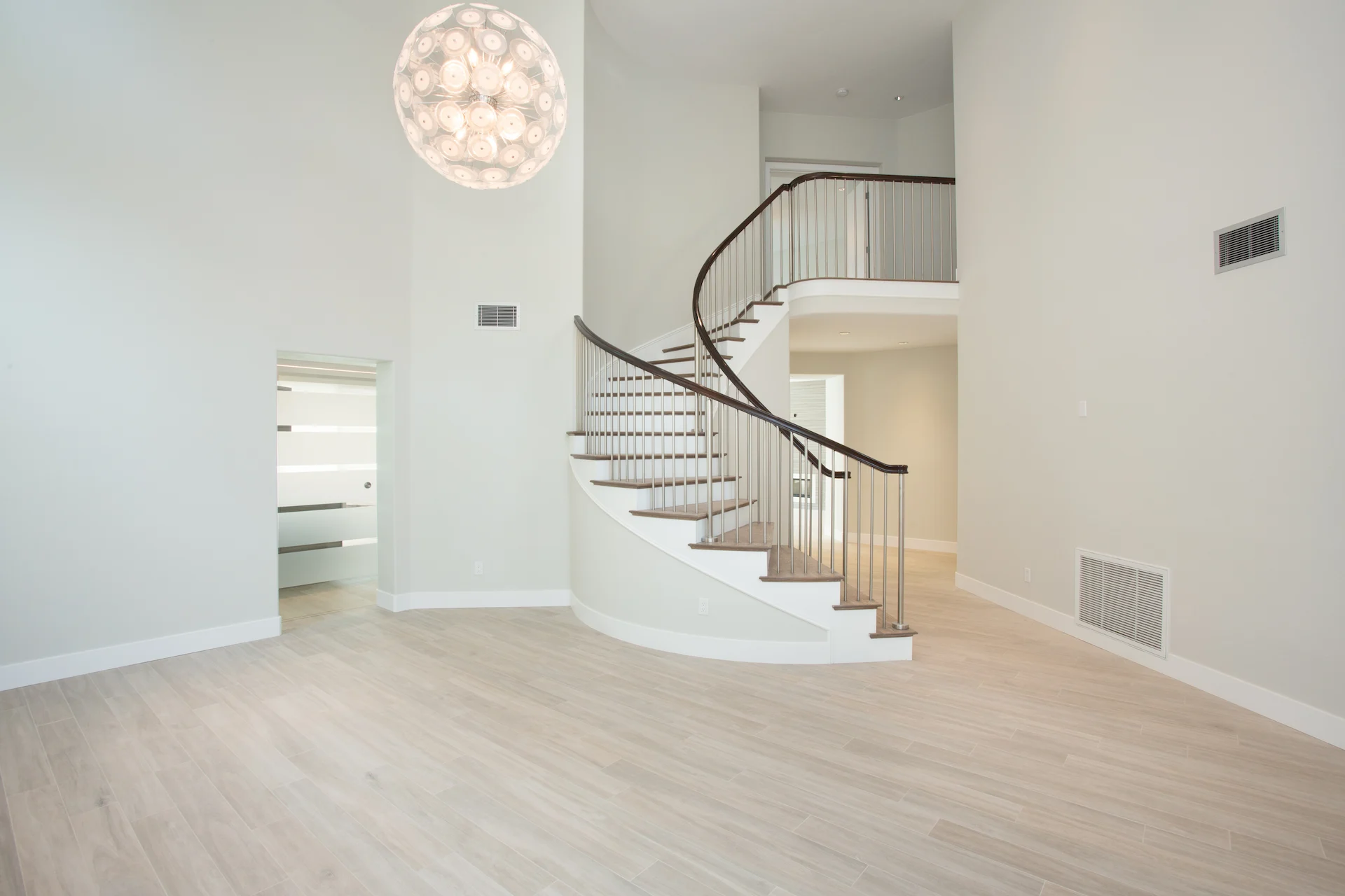 Wide view of the main entry featuring the spiral staircase with solid oak treads and brushed stainless steel pickets, a centerpiece in this Harbor Cove home.