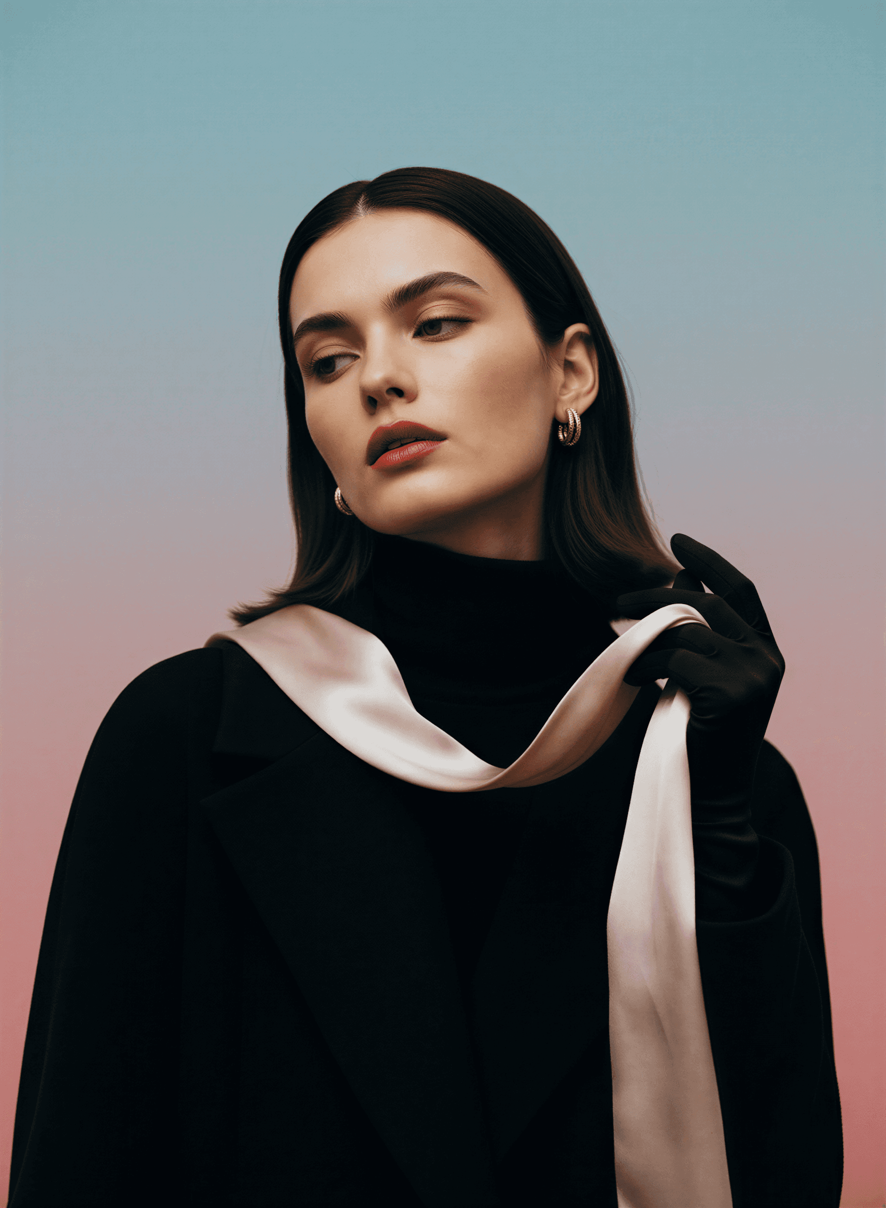 A woman in a black coat with a pale silk scarf, looking away