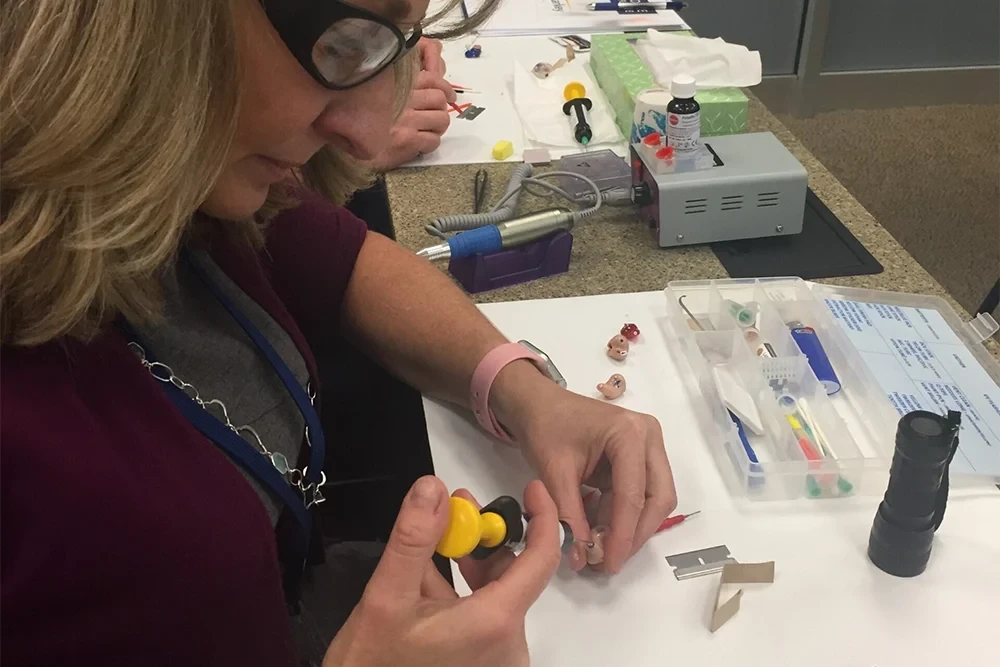 Two people are closely examining small objects at a table, engaged in a hands-on activity.