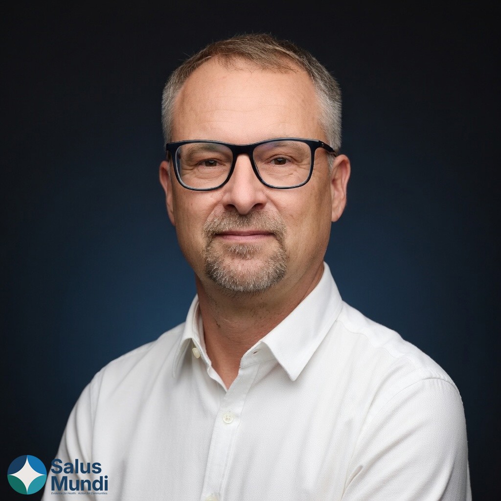 Smiling man wearing glasses and a pink shirt, showing his arm with a bandage after vaccination.