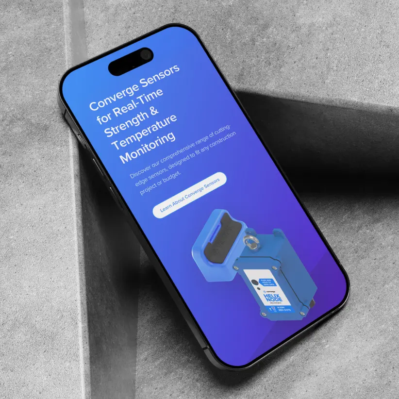 Phone on concrete surface displaying Converge product webpage promoting real-time strength and temperature monitoring sensors.