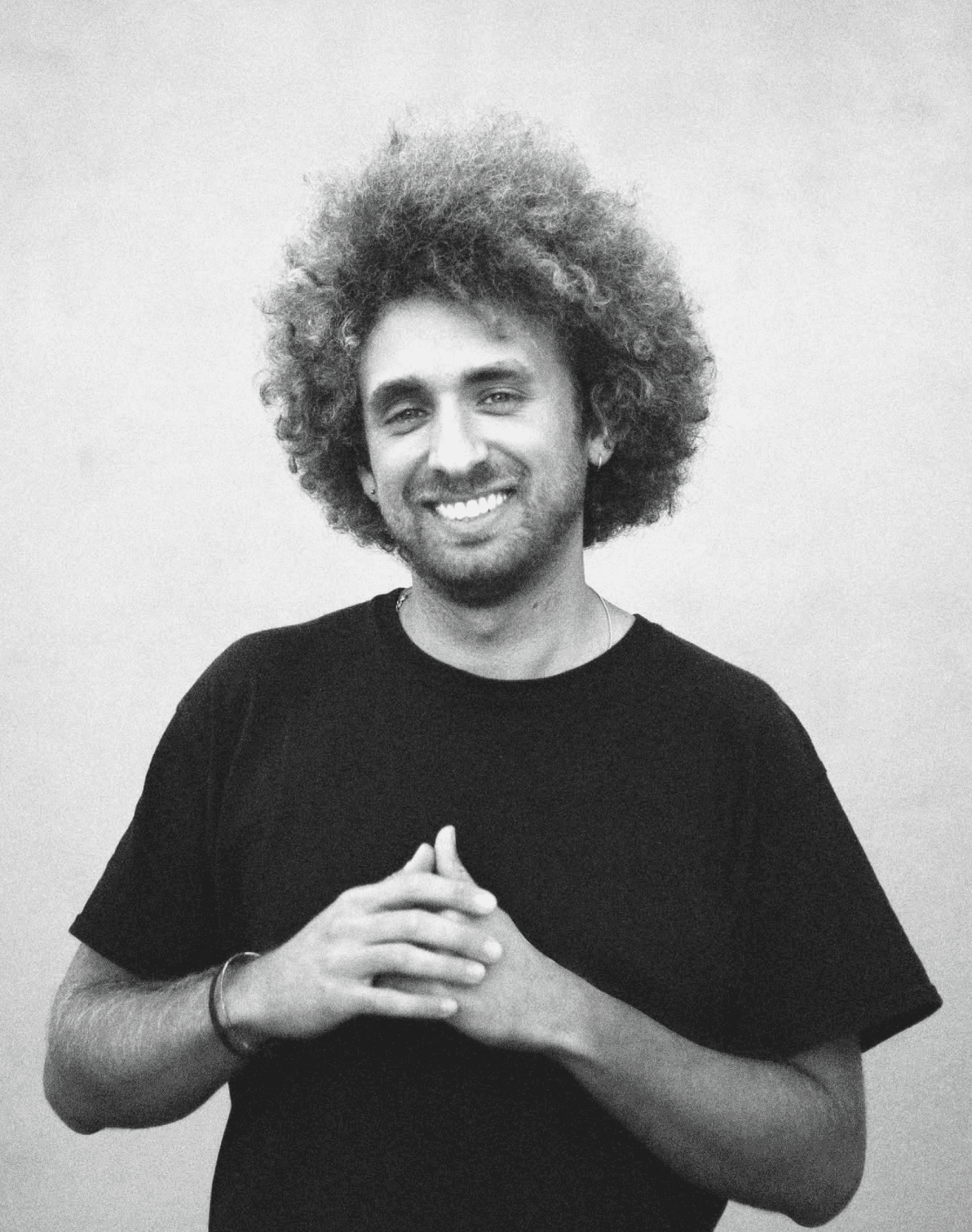 A thoughtful young person with dark hair gazes to the side, captured in soft black and white lighting.