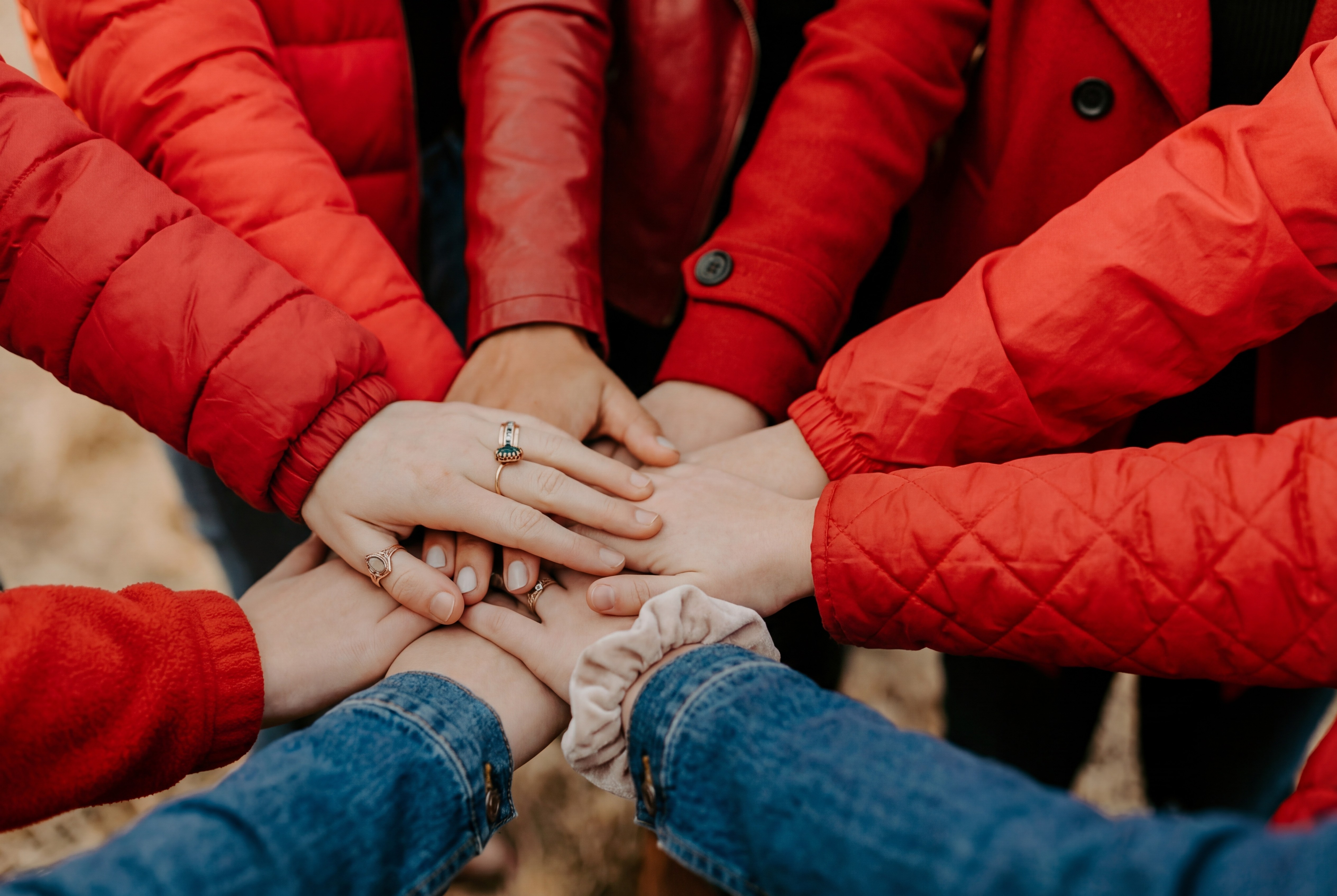 A smiling woman with her arms crossed, standing against a dark green background. She has long, dark hair.