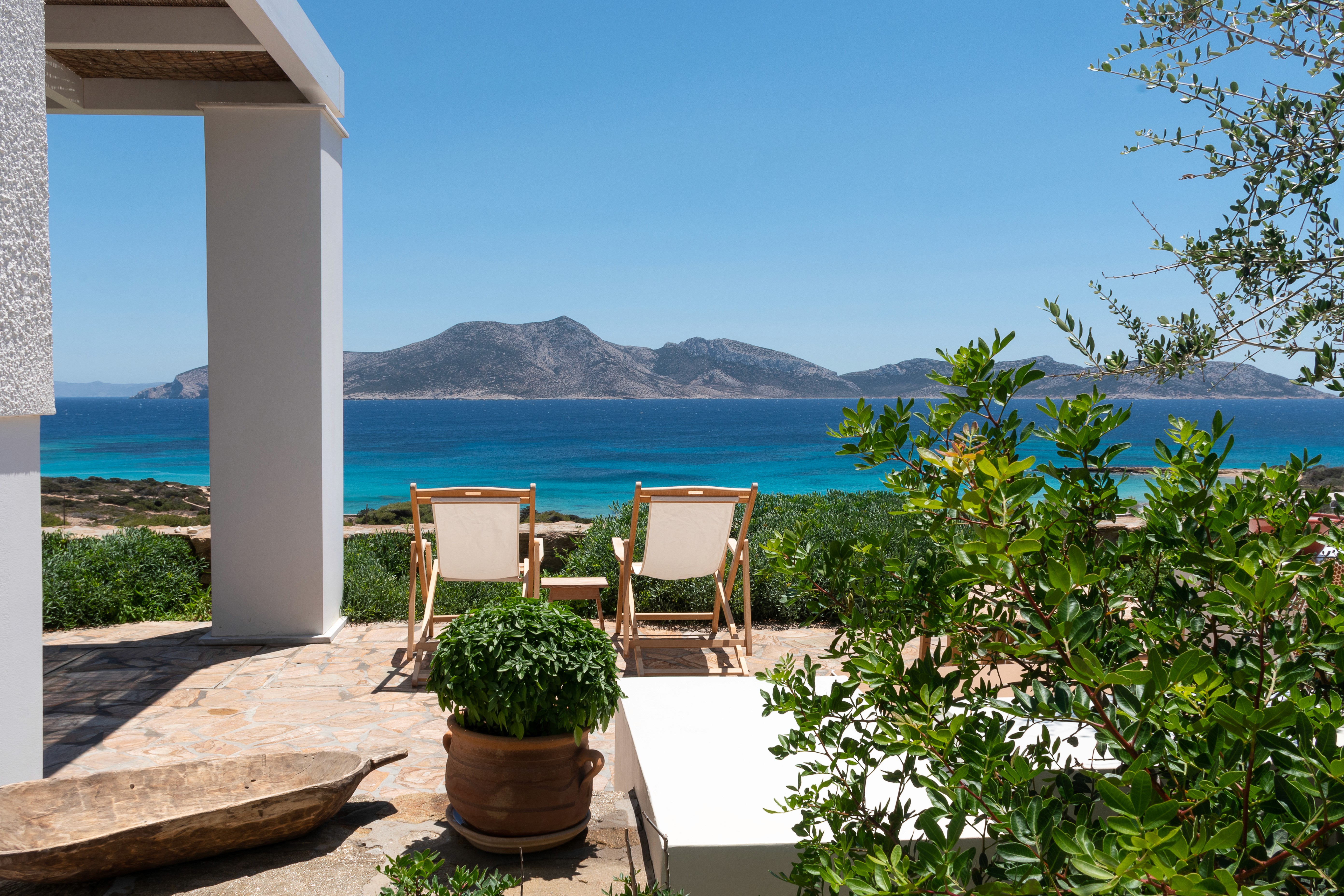 The private terrace of a house by the sea with two deck chairs and plants with views of the sea and the island of Keros