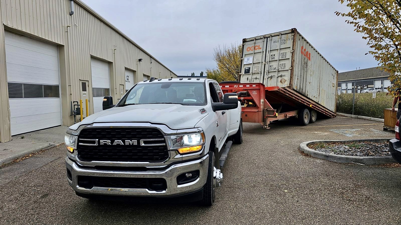 20-foot used shipping container being unloaded from tilt deck trailer