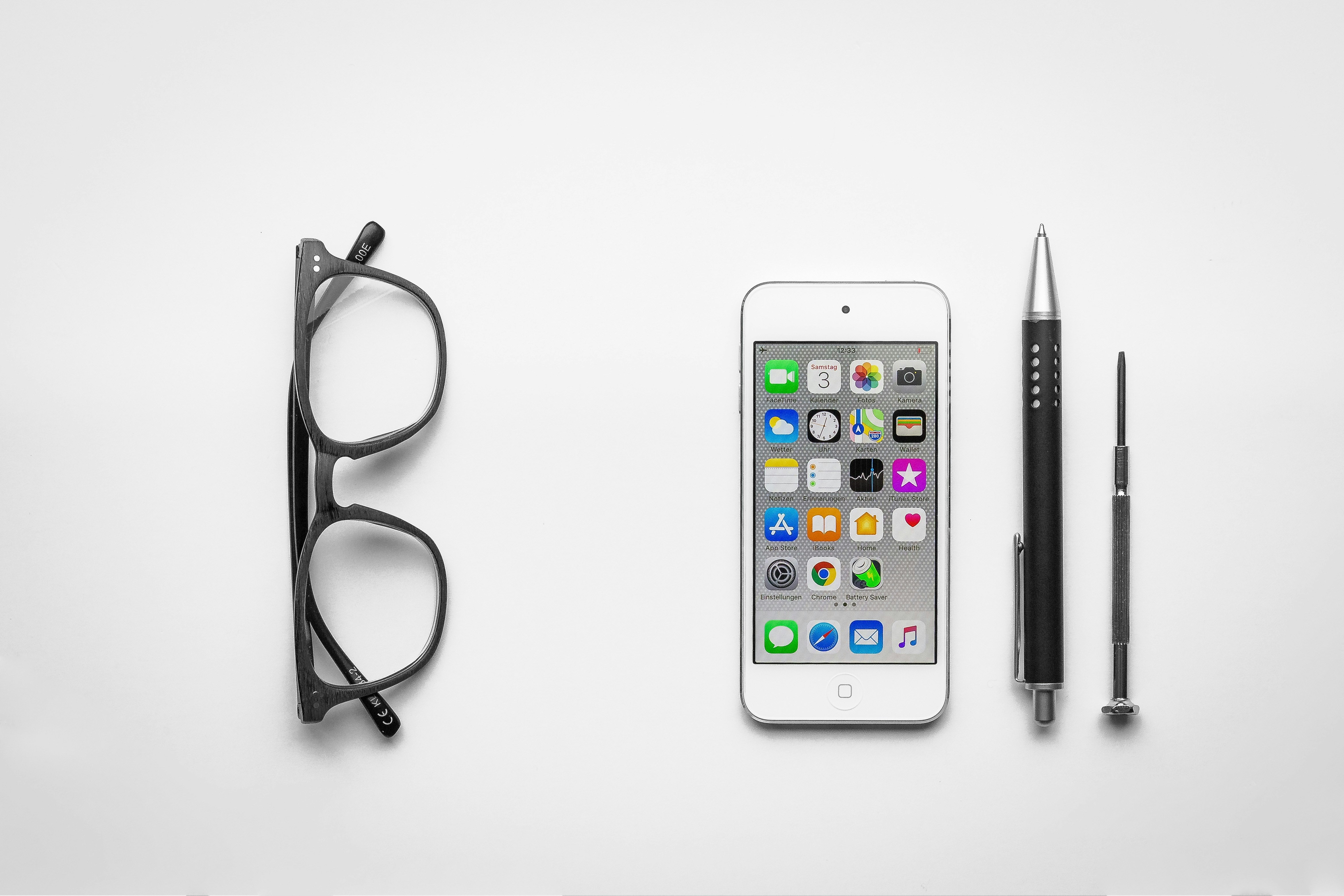 white iPhone beside click pen and glasses