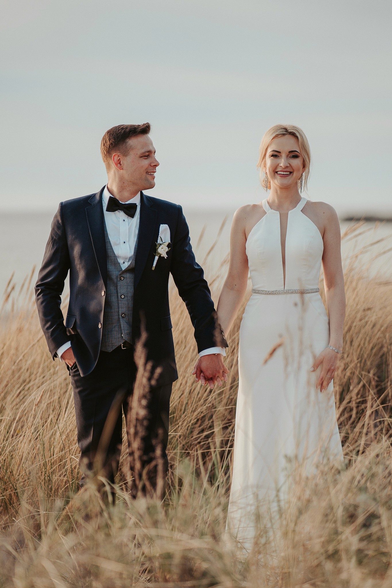 A person with shoulder-length blonde hair wearing a black newsboy cap and a black sweater.