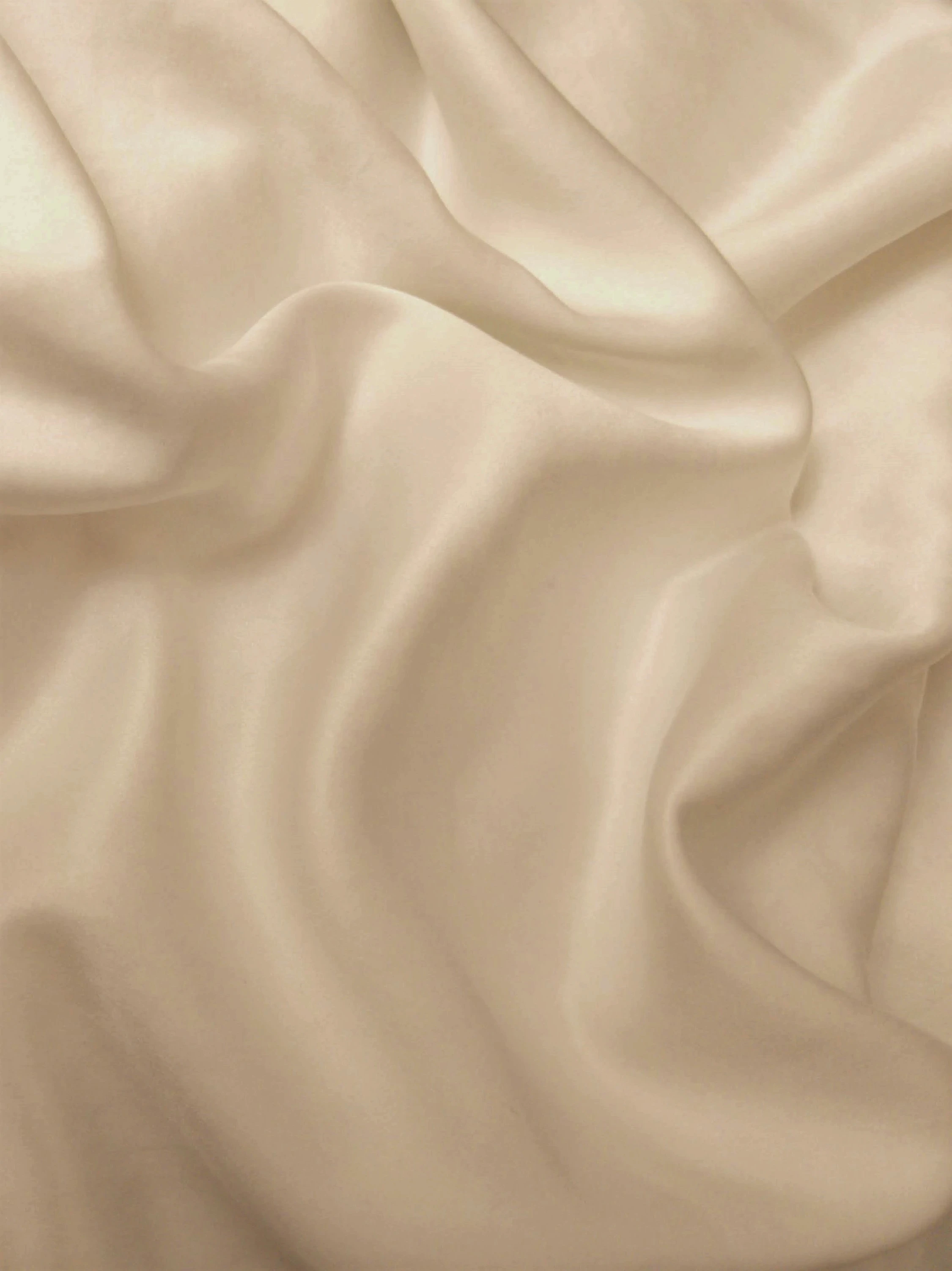 Gentle waves of soft beige satin fabric, representing the fluid elegance and feminine spirit of the collection.