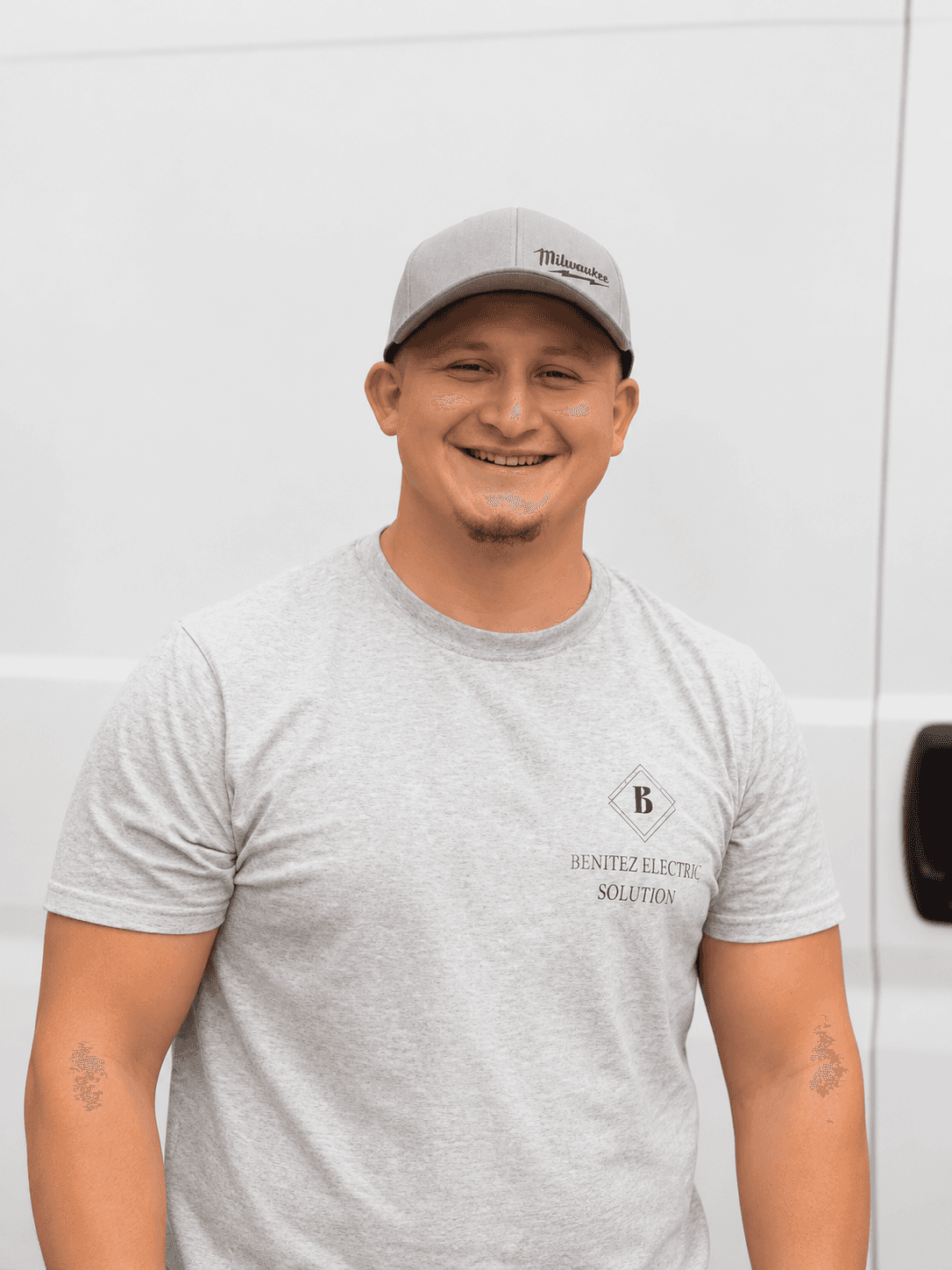 Experienced electrician in white hard hat smiling in front of electrical control panel