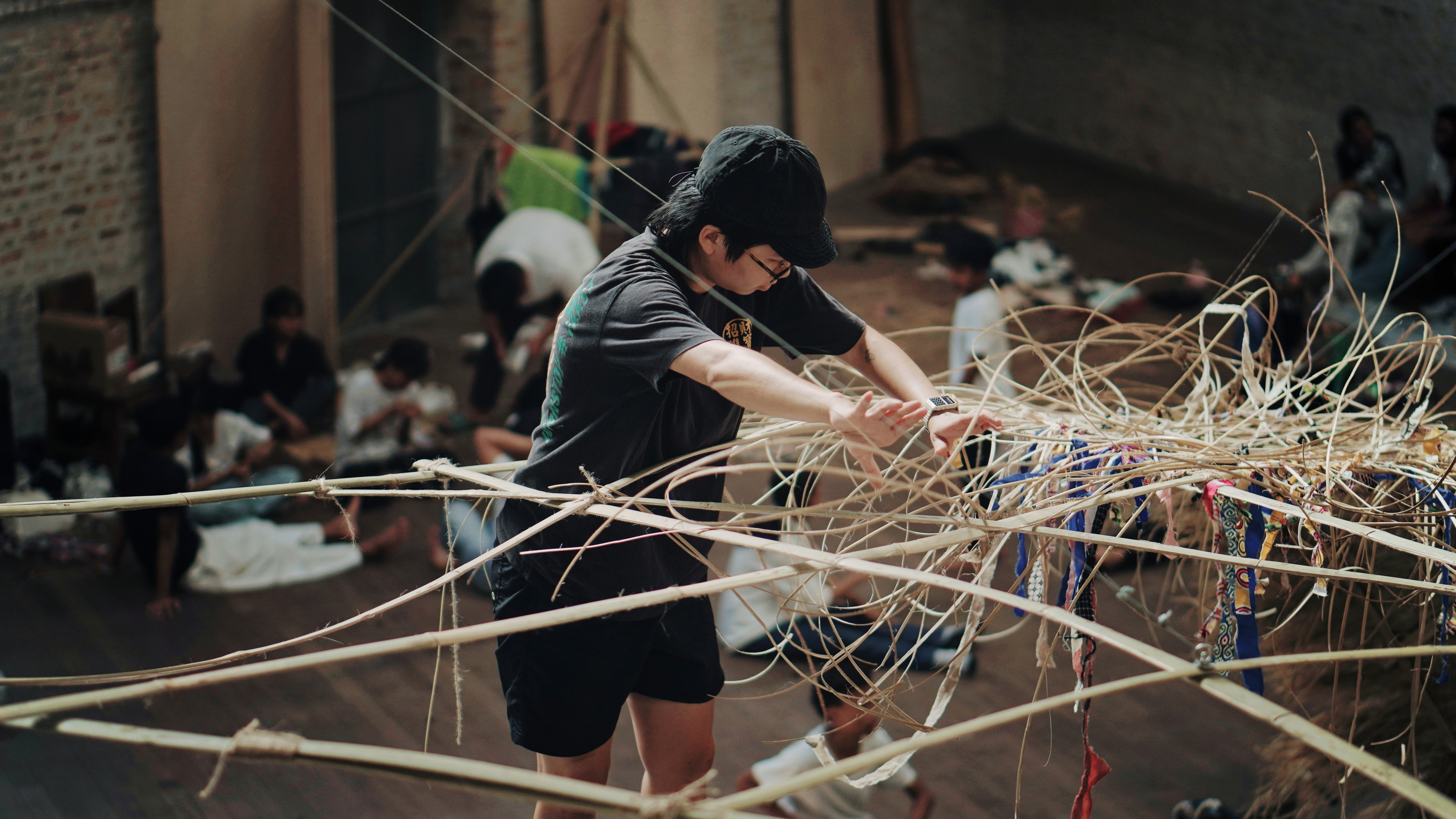 a person weaving rattan high up in a hall