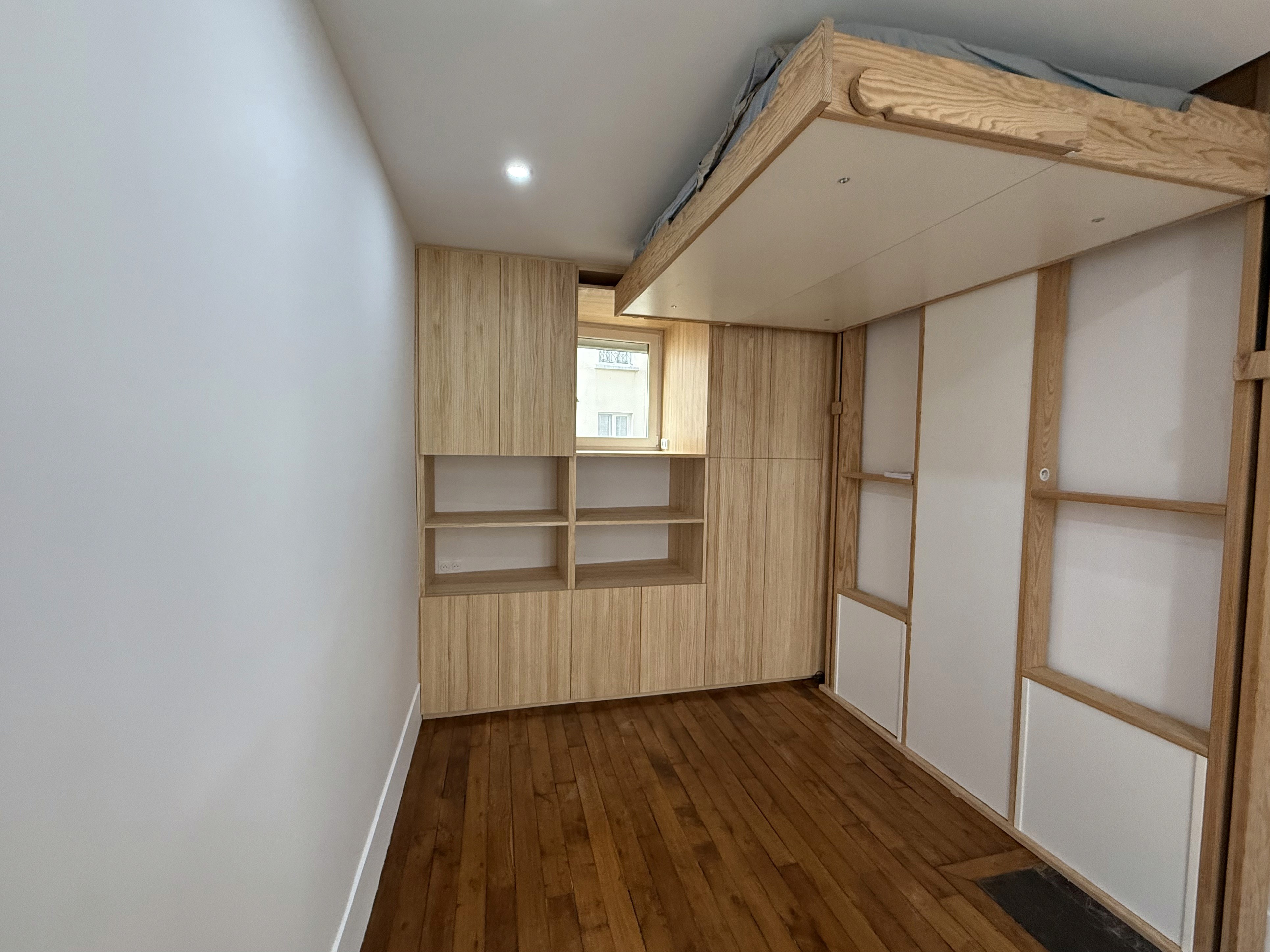 Structure de lit mezzanine sur-mesure sculptant l'espace pour créer une zone de couchage en hauteur.