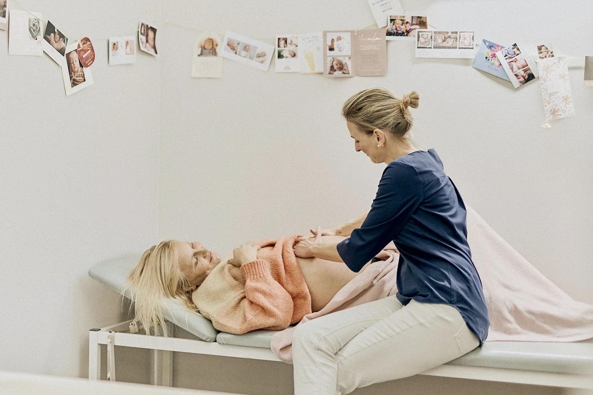 Hebamme Karolin Rustler bei einer einfühlsamen Untersuchung einer Schwangeren in der Frauenarztpraxis Dr. med. Angela Lauten, spezialisiert auf Pränataldiagnostik und Frauenheilkunde in Erfurt.