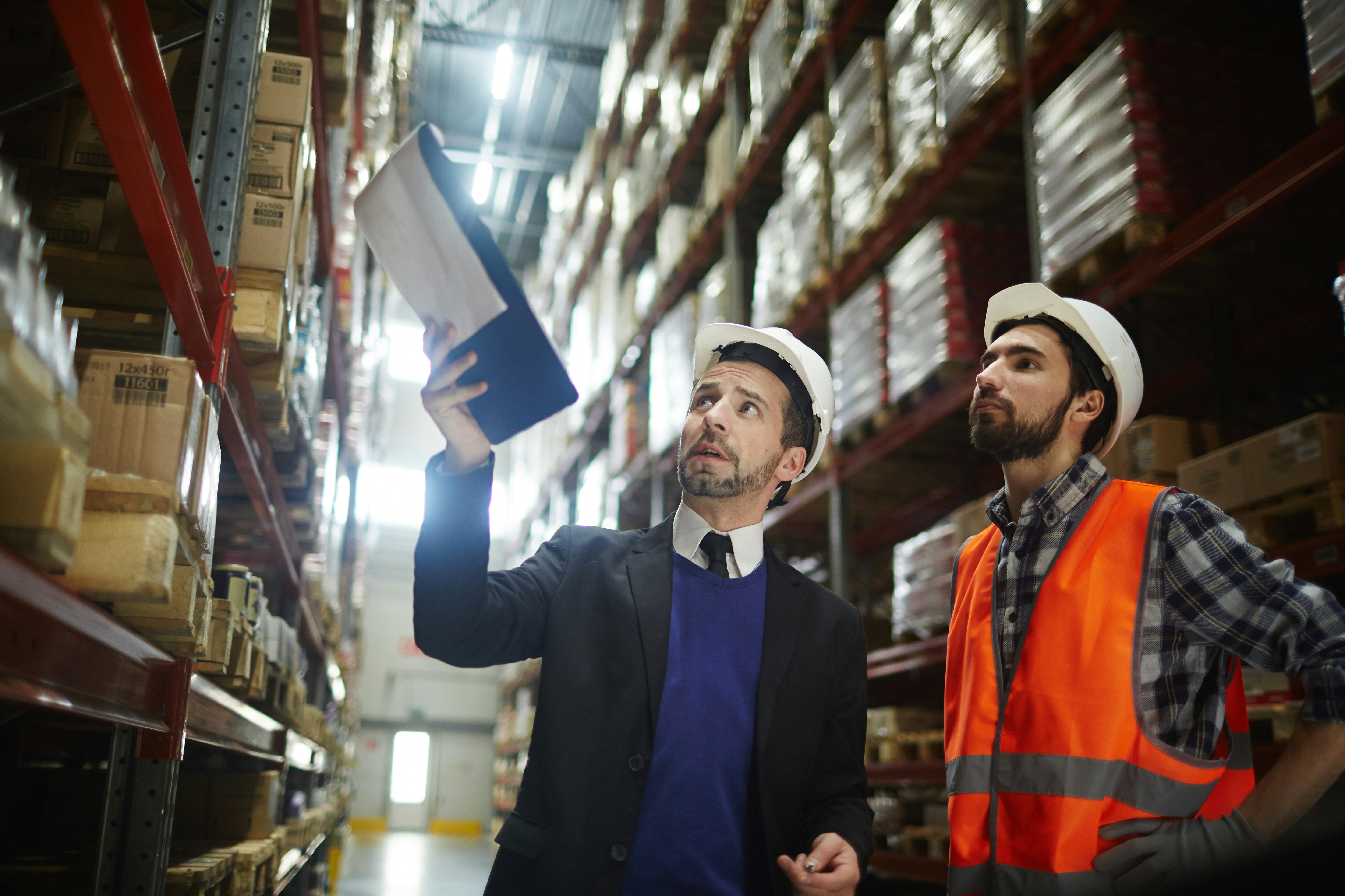 two men look up at something on warehouse shelving