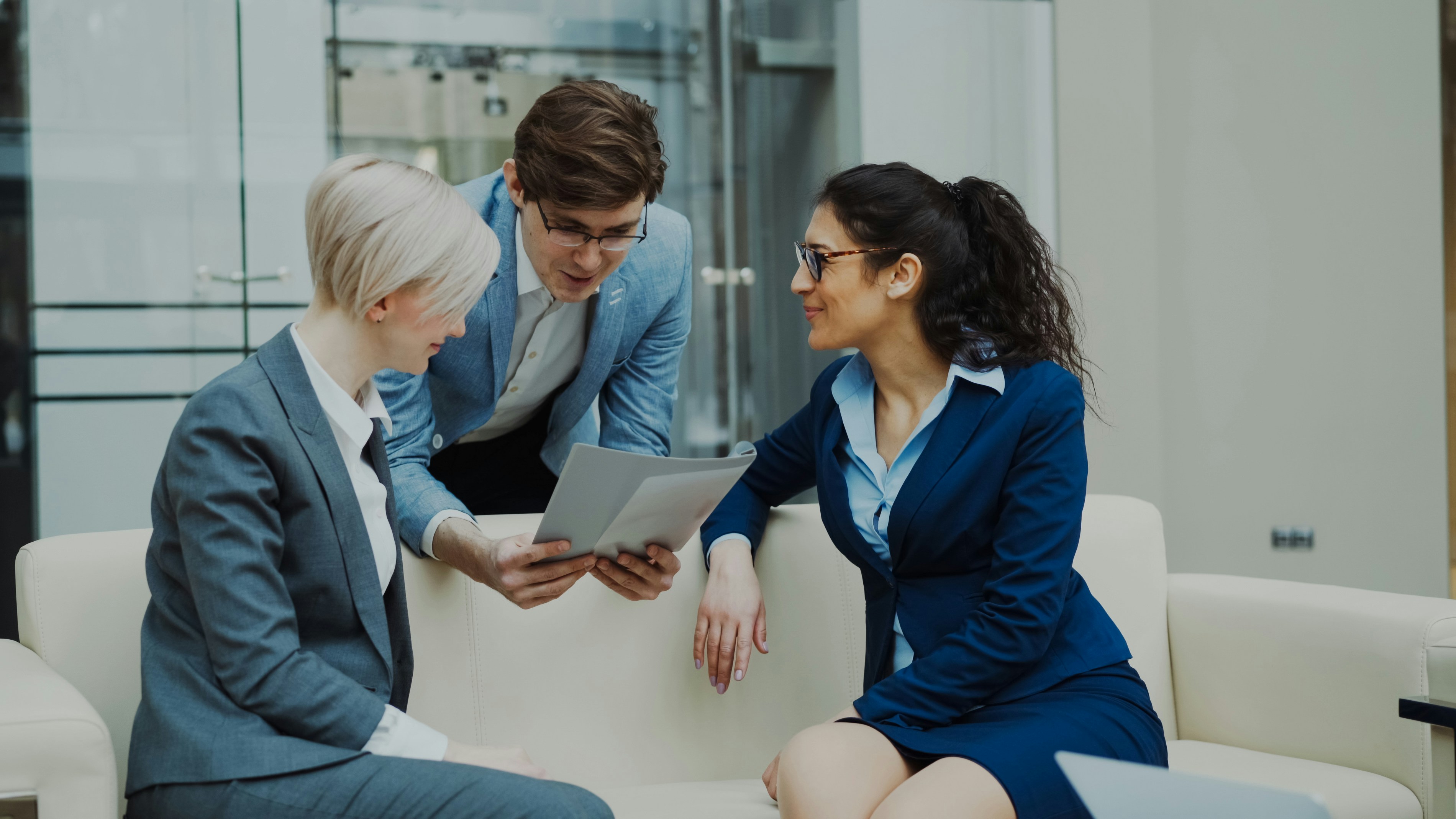 Three business people in suits discussing documents.
