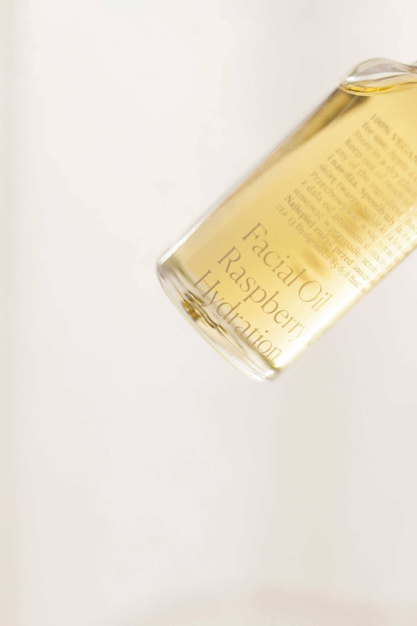 A detailed view of a glass bottle showing the screen-printed text for "Facial Oil Raspberry Hydration." This highlights the studio’s attention to typographic detail and durable, high-quality labeling for liquid beauty products.